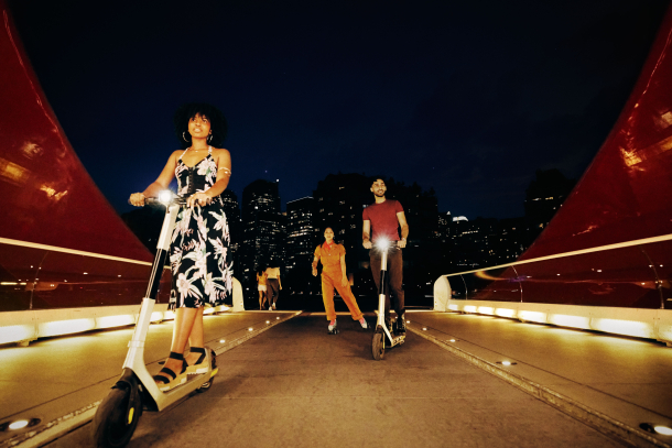 People scootering and roller-skating across the Peace Bridge in Calgary at Night