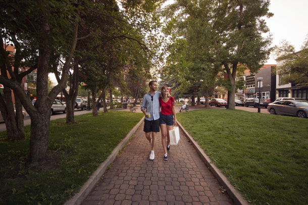 Couple walking a tree-lined street on 17th Ave with shopping bags