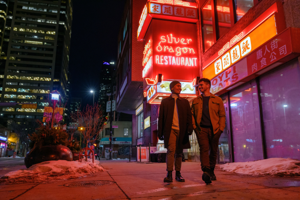 couple walks outside of Silver Dragon Restaurant underneath the restaurants lit neon sign at night