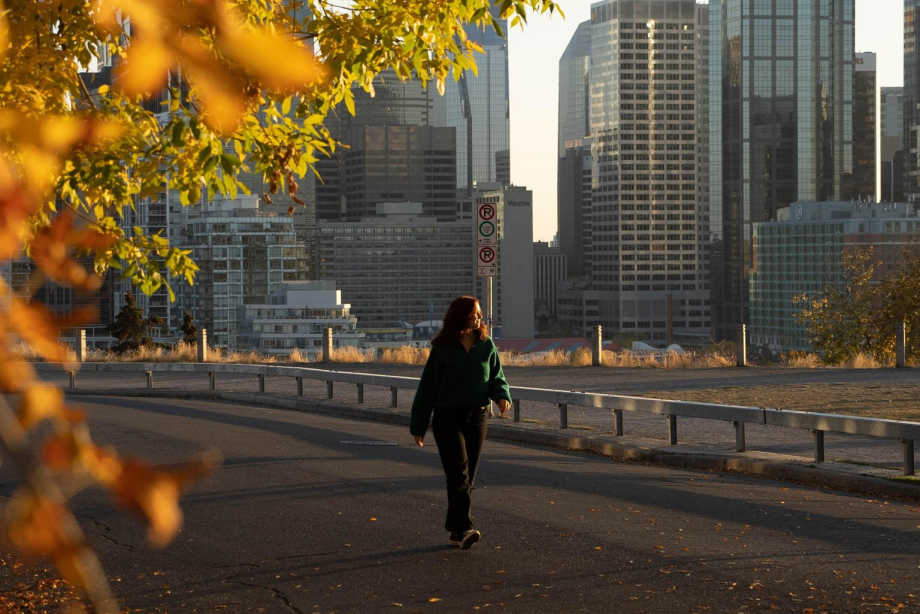 Woman walking through Crescent Heights in fall, with Calgary skyline in the background