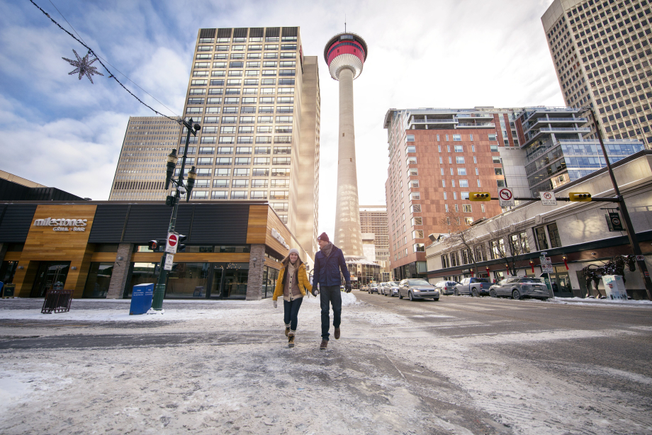 Couple walking on Stephen Avenue in the winter, with the Calgary Tower in the background