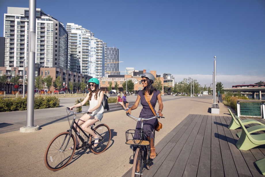 Two women riding bikes along the Riverwalk in downtown Calgary's East Village
