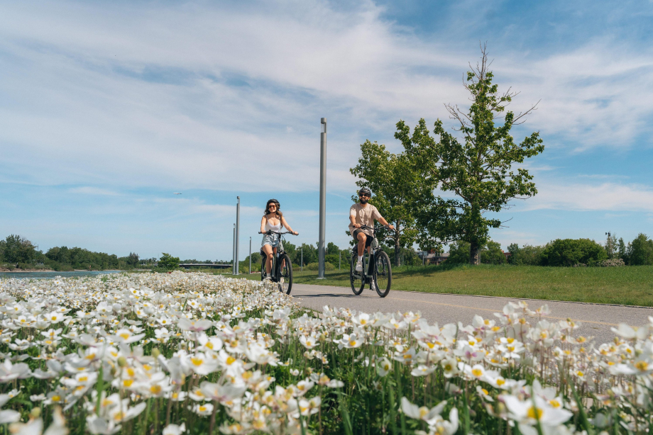 A male and a female cycling on a summer day along the bow river pathway in East Village