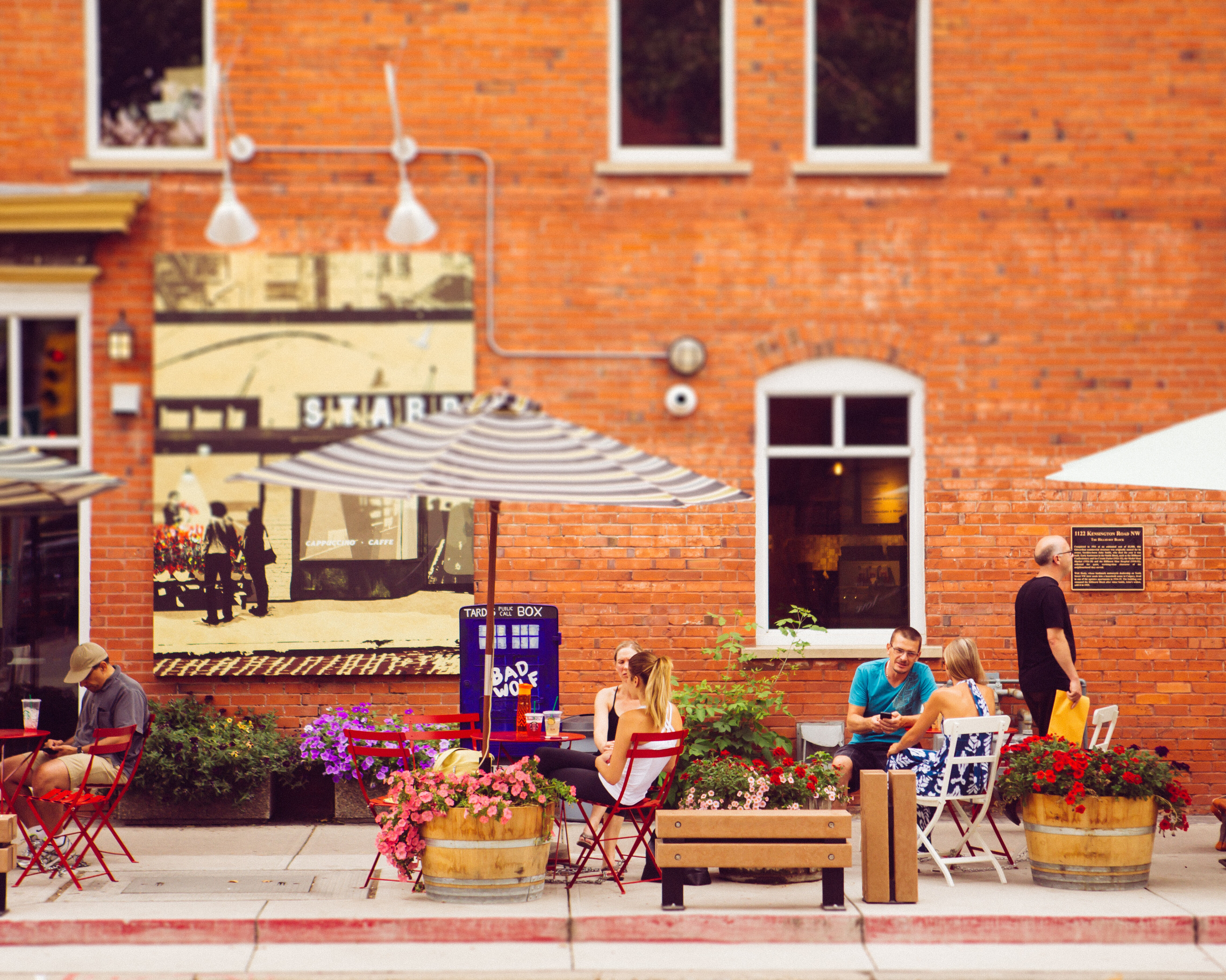 People sitting at patio tables on a sidewalk in the Kensington neighborhood in Calgary