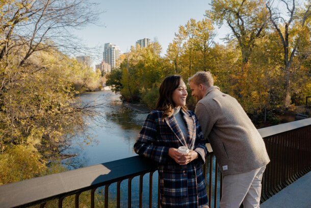 Couple at a bridge over the river with the downtown in background