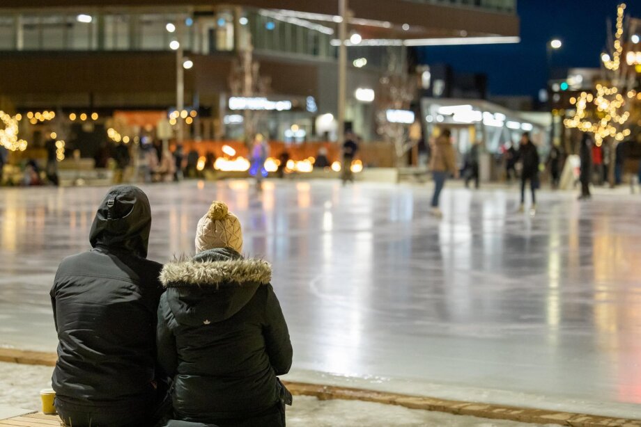Two people watching skating on the University District rink.