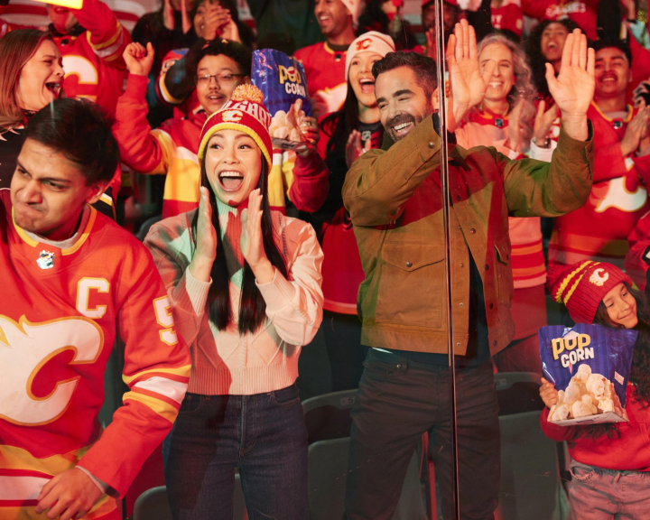 Excited Calgary Flames fans cheering in team jerseys at the Scotiabank Saddledome during a home game