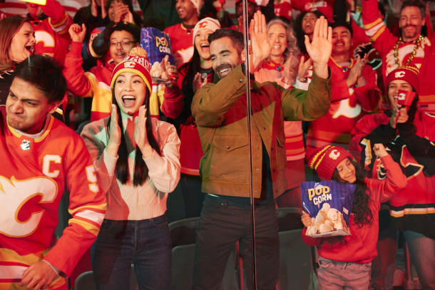 Excited Calgary Flames fans cheering in team jerseys at the Scotiabank Saddledome during a home game