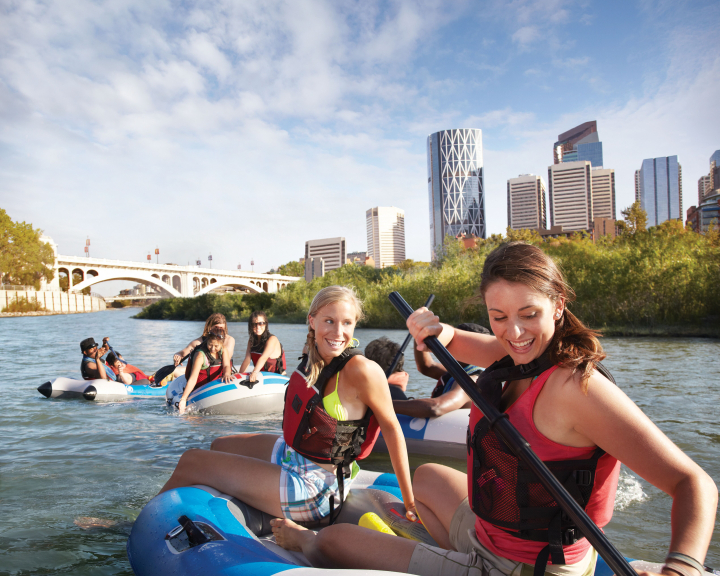 Group of young women rafting down the Bow River in Calgary with the city skyline in the background