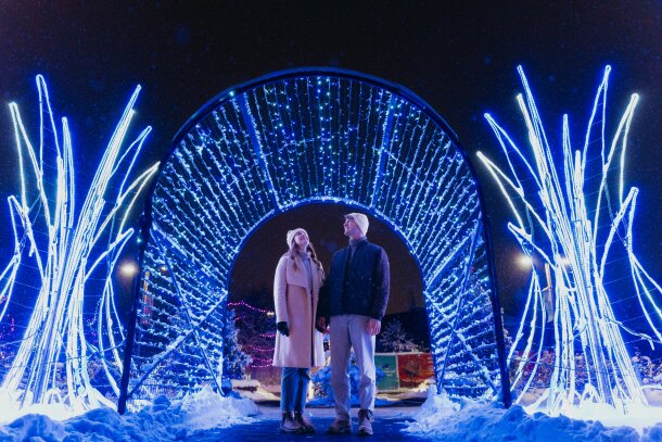 a couple standing in front of a tunnel of lights at ZOOLIGHTS at the Calgary Zoo