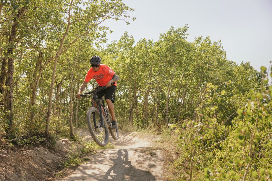 A man mountain biking through the forest at WinSport.