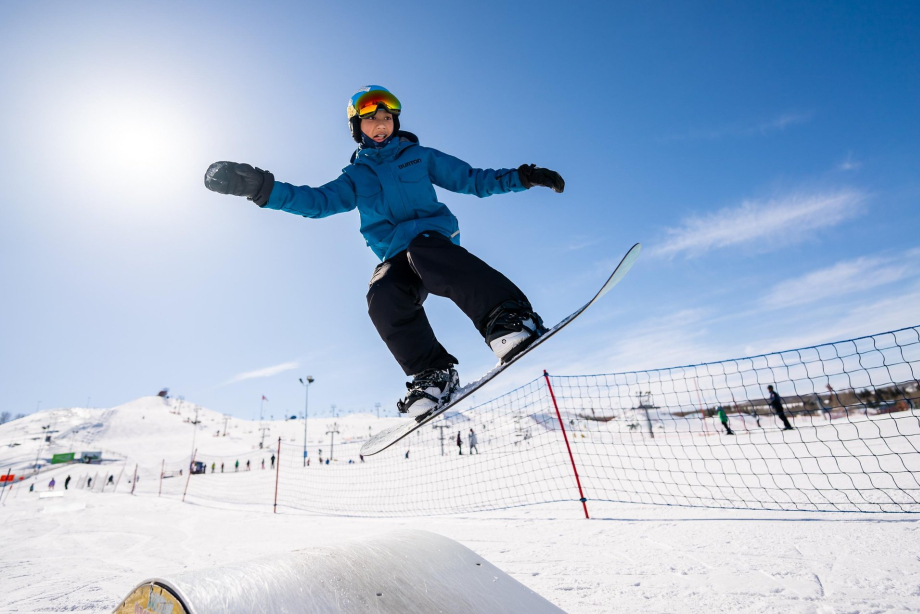 child taking a snowboard jump at WinSport