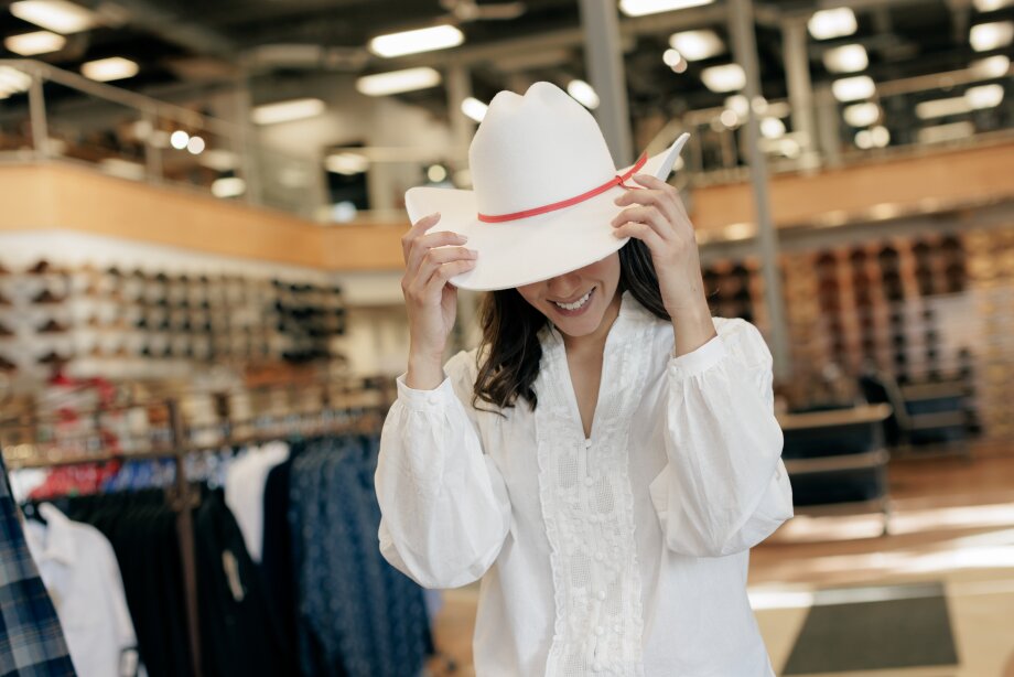 a woman is trying on a Smithbilt hat in Inglewood