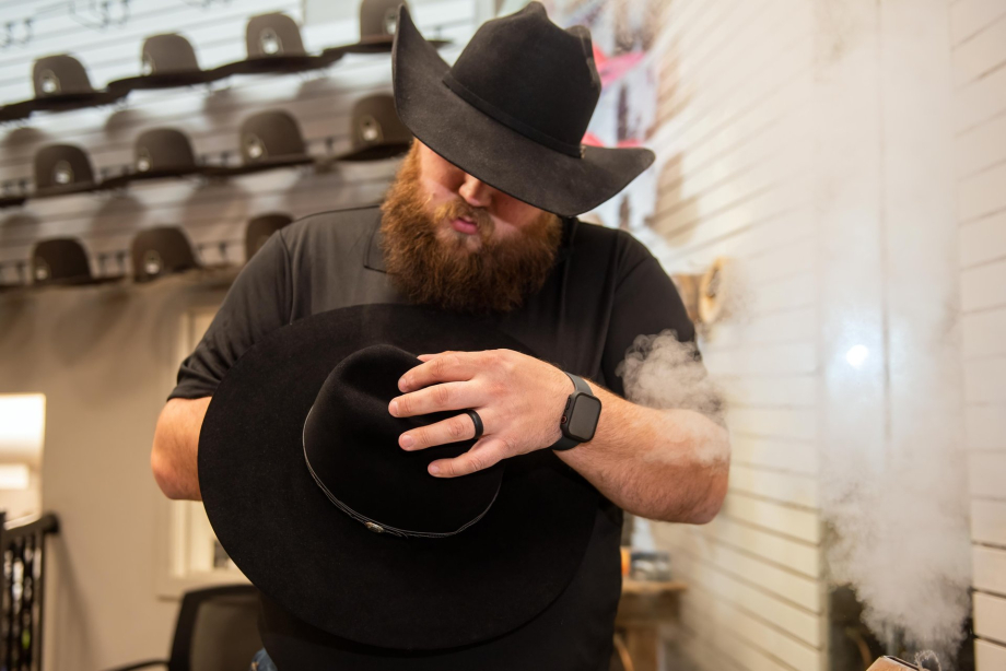 Man wearing a cowboy hat steaming a cowboy hat