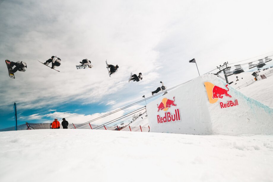 Snowboarders mid-flip on a snow hill