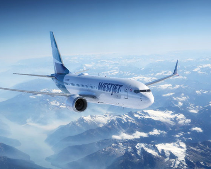 WestJet plane flying over the Canadian Rockies