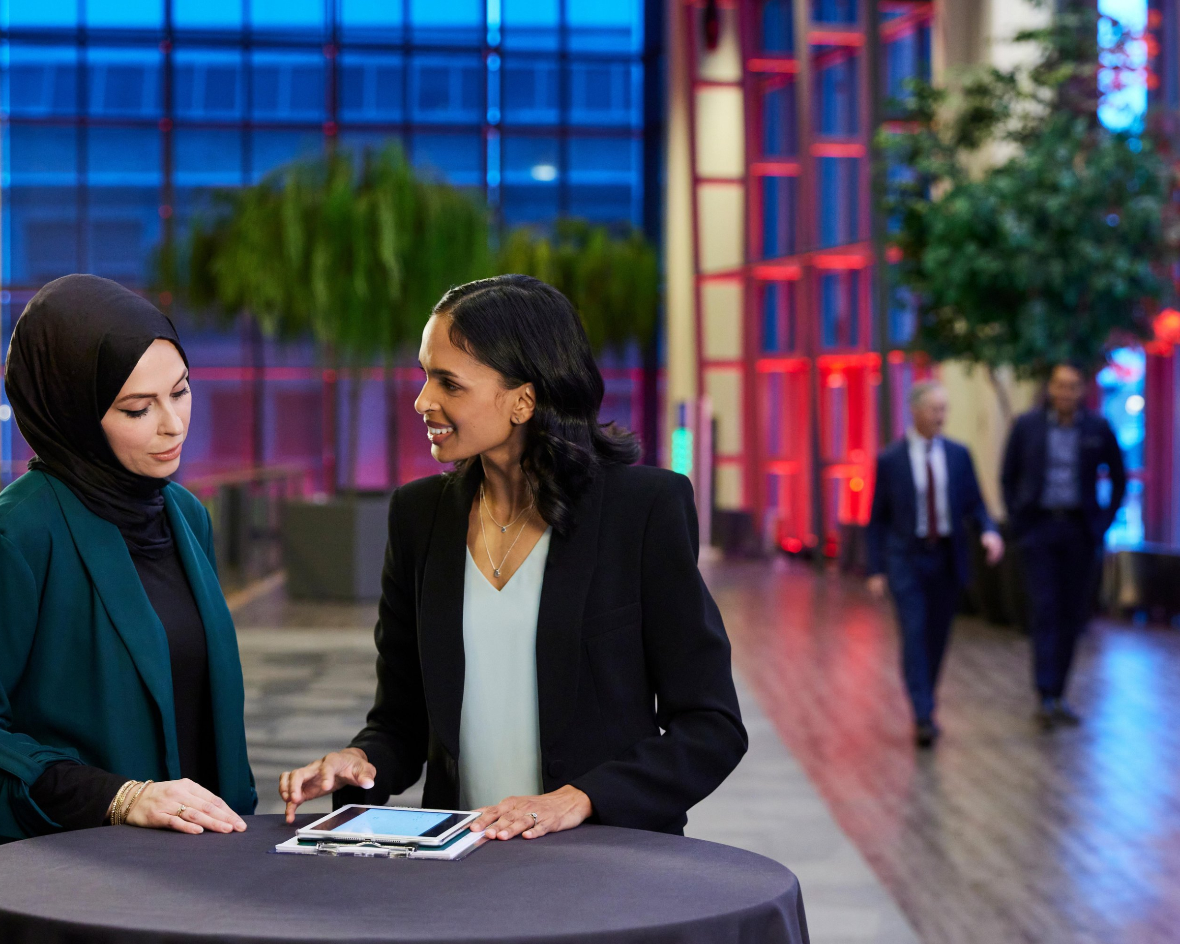 Two women at a cocktail table looking at an ipad
