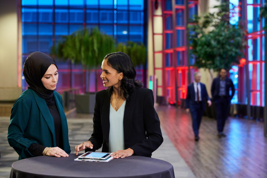 Two women at a cocktail table looking at an ipad
