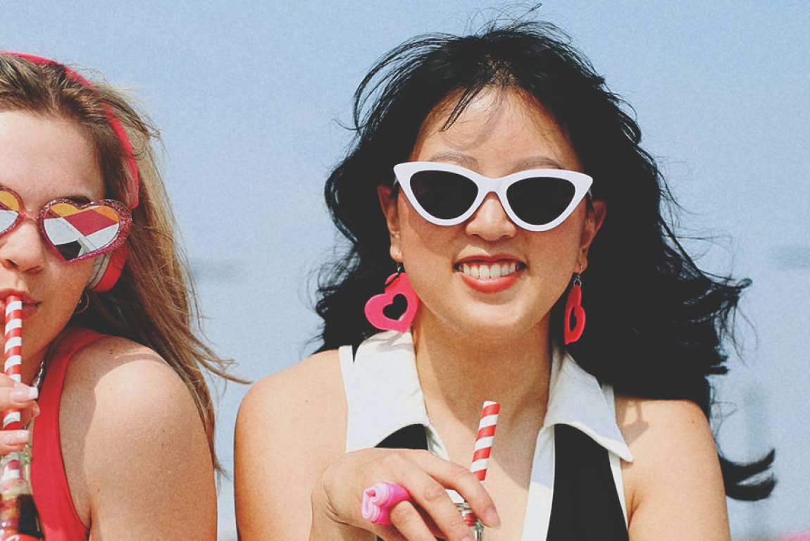 2 girls in sun glasses sipping bottled coke in the summer